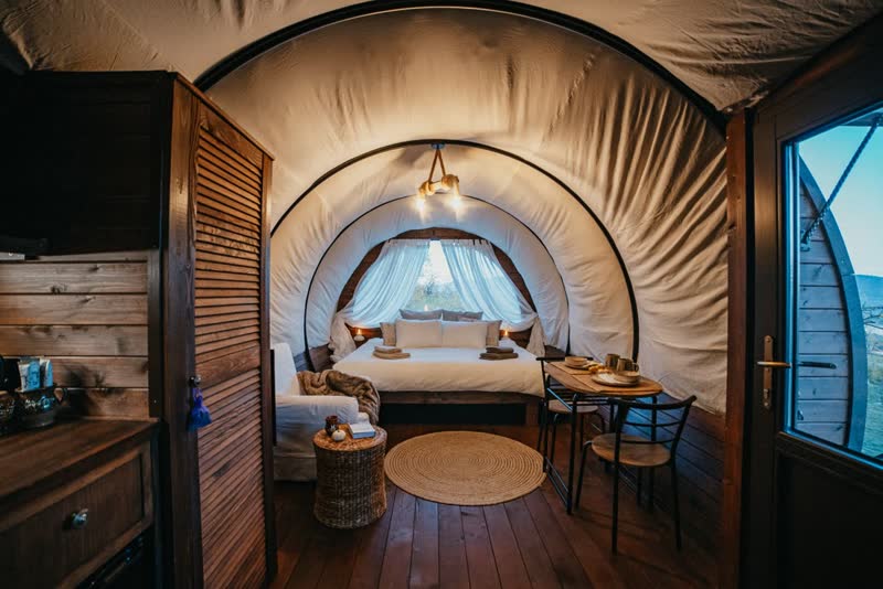 Glamping szekér belső tere faburkolattal, ággyal és ablakokkal
